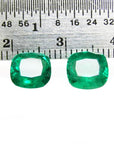 Matched pair of vibrant green cushion cut emeralds, 3.36 carats total, displayed with a ruler for scale.
