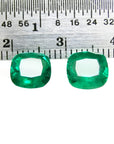 Matched pair of vibrant green cushion cut emeralds, 3.36 carats total, displayed with a ruler for scale.