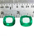 Matched pair of vibrant green cushion cut emeralds, 3.36 carats total, displayed with a ruler for scale.