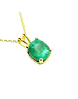 A cushion cut natural colombian emerald solitaire pendant prong set in a 14k yellow gold setting.
