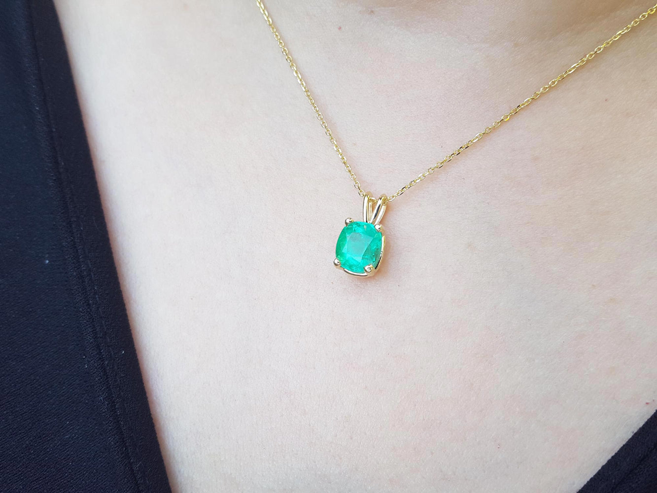 Gold necklace with an authentic Colombian emerald pendant on a person's neck.