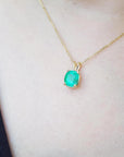 Gold necklace with an authentic Colombian emerald pendant on a person's neck.