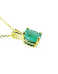 Cushion cut natural emerald solitaire pendant in 14K yellow gold with four-prong setting.