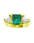 18k yellow gold ring with a square emerald and two trillion-cut diamonds.