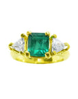 18k yellow gold ring with a square emerald and two trillion-cut diamonds.