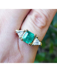 Women's ring with a center natural colombian emerald and two trillion side diamonds, crafted in 18k yellow gold.