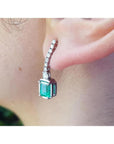 18K white gold dangling earrings with emerald-cut Colombian emeralds and diamond studs.