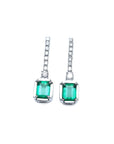 18K white gold dangling emerald-cut emerald earrings with diamond-studded lines.