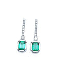 18K white gold dangling emerald-cut emerald earrings with diamond-studded lines.