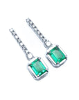 Pair of emerald dangle earrings with 14k white gold settings right side position top view
