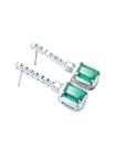 Dangling 18K white gold earrings with emerald-cut Colombian emeralds and diamond studs.