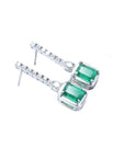 Dangling 18K white gold earrings with emerald-cut Colombian emeralds and diamond studs.