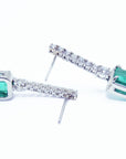 Pair of 18k white gold emerald dangle earrings underside and upside-down view