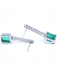 18K white gold dangling emerald-cut emerald earrings with diamond-studded straight lines.
