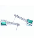 18K white gold dangling emerald-cut emerald earrings with diamond-studded straight lines.