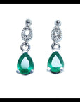 Dangling teardrop emerald earrings in 14K white gold with diamond-studded pear links.