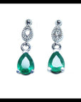 Dangling teardrop emerald earrings in 14K white gold with diamond-studded pear links.