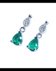 Left side profile of a pair of pear cut emerald dangle earrings in 14l white gold