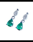 Dangling teardrop emerald earrings with diamond-studded pear links in 14K white gold.