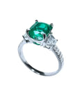 Anillo de compromiso de oro blanco 18k con esmeralda colombiana ovalada y diamantes trapezoide.