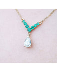 14K gold necklace with a 0.69 ct pear diamond and 0.35 ct round emeralds in a V-shape.