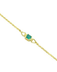 The distant view of a gold bracelet with a genuine emerald on a distant view.