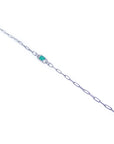 A distant view of a white gold paperclip emerald bracelet.