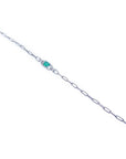A distant view of a white gold paperclip emerald bracelet.