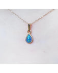Pear-shaped Australian doublet opal pendant with bluish-green sparkle, bezel set in 14K yellow gold on a chain.
