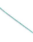 A distant view of a colombian emerald tennis bracelet in white gold on a white background.