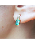 14K yellow gold emerald earring with baguette-cut emerald and diamond accents on an ear.