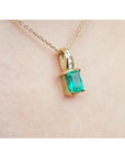 A right-side profile view of an emerald pendant on a skin background