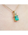 14K yellow gold pendant with an emerald-cut green emerald and diamond accents on a delicate chain.