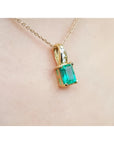 14K yellow gold pendant with an emerald-cut green emerald and diamond accents on a delicate chain.