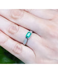 0.90 ct. East West emerald ring in 14k white gold with diamond accents, worn on a hand.