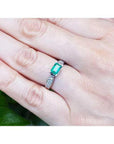 0.90 ct. East West emerald ring in 14k white gold with diamond accents, worn on a hand.