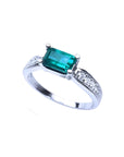 East West emerald ring with a vivid green rectangular emerald and diamond accents on a 14k white gold band.