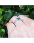 East-west emerald ring with a vivid green stone and diamond accents on a 14k white gold band.