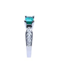 East-west emerald ring with a vivid green emerald and diamond accents on a 14k white gold band.