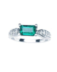 A Mother’s Day emerald white gold ring in an east-west style, featuring accent diamonds along the band.