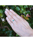 14K white gold ring with a bezel-set east-west teardrop emerald and diamond accents.