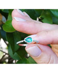 14K white gold ring with a bezel-set east-west teardrop emerald and prong-set accent diamonds.