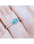 East-west teardrop emerald ring with bezel setting and diamond-accented 14K white gold band.