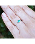 14K white gold ring with a bezel-set east-west teardrop emerald and diamond accents.