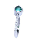The perspective side view of a teardrop emerald bezel set ring with studded diamonds on the band.