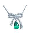 18K white gold bow-tie necklace with a deep green pear-shaped emerald pendant.