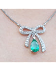 18K white gold bow-tie necklace with a pear-shaped deep green emerald pendant.