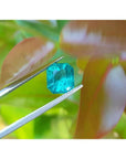2.95 ct square natural Colombian emerald, bright medium green, held by tweezers.