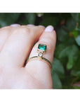 14K yellow gold ring with a bezel-set emerald dangle and a small diamond accent.