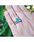 1.48 ct. emerald engagement ring with diamond wedding band set in 14K white gold on a hand.